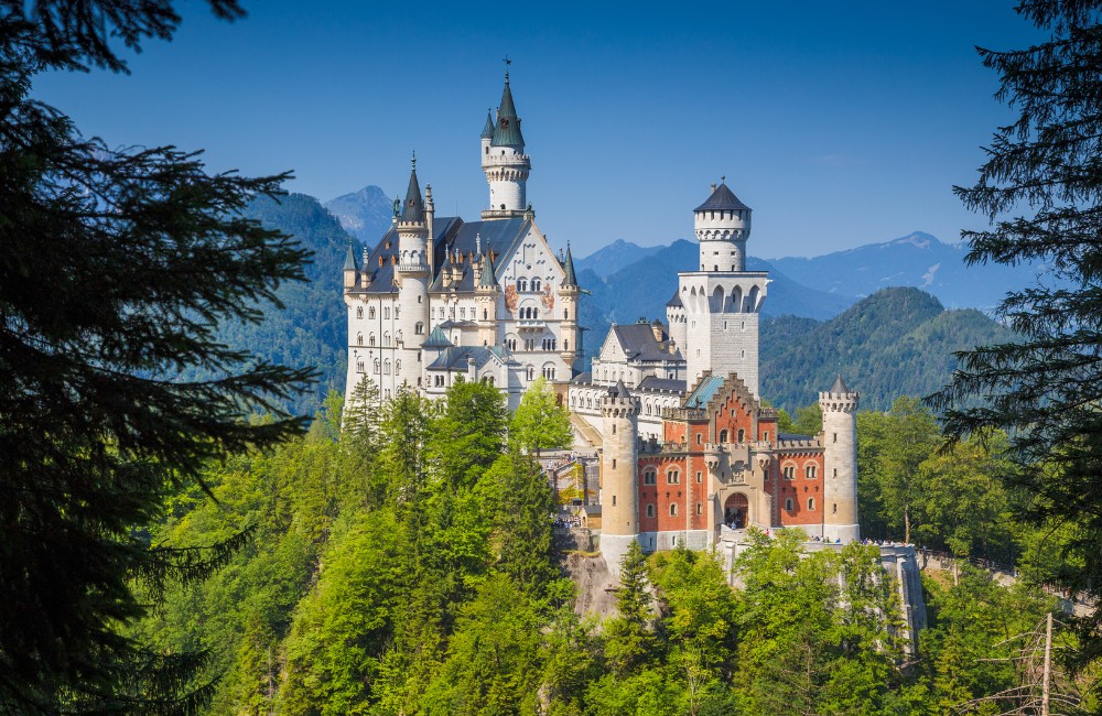 Castello di Neuschwanstein arroccato su una cresta rocciosa circondato dalla foresta